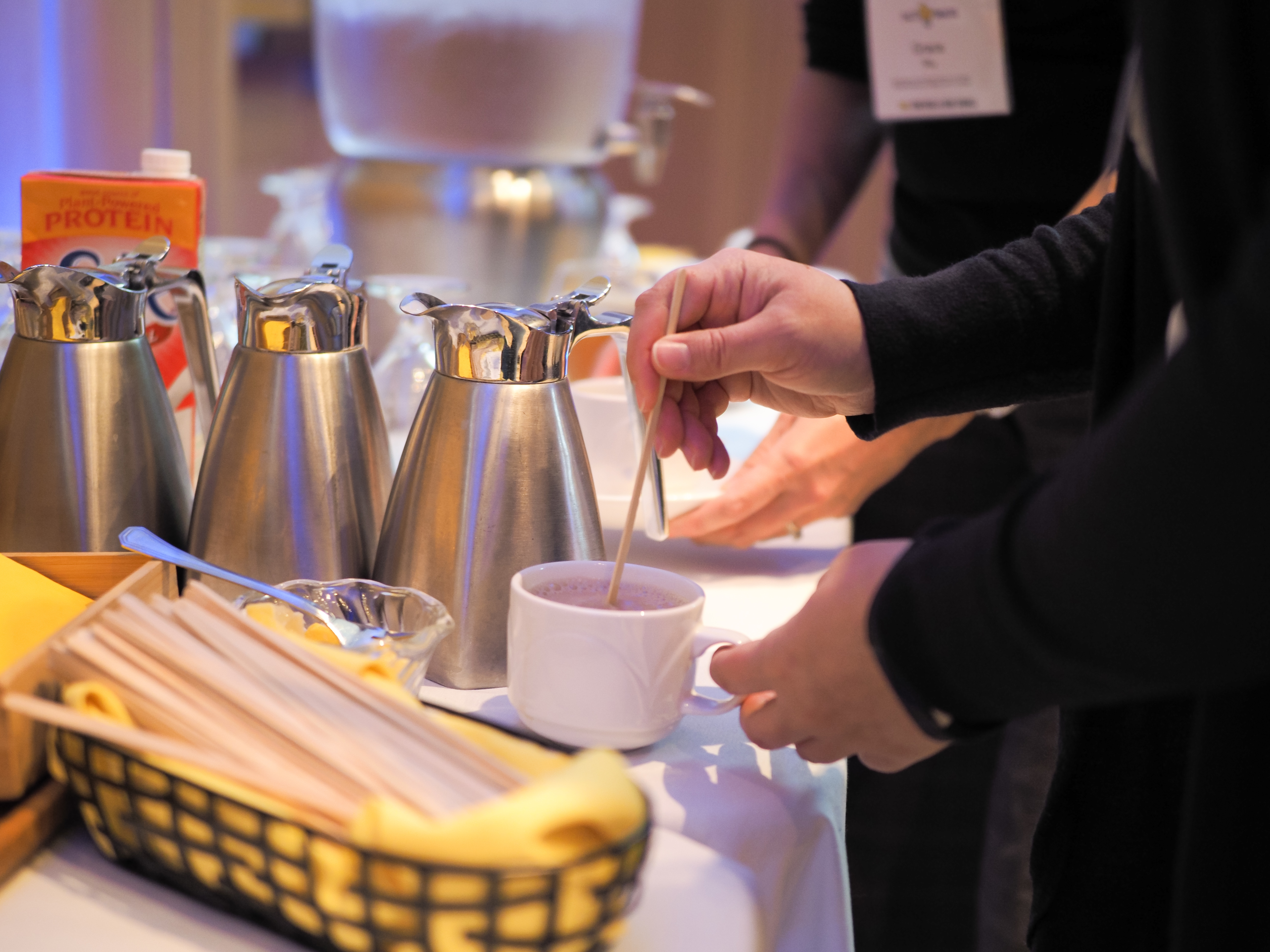 People serving coffee with wood stirrers